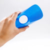 A hand is holding a bright blue soccer training disc cone with a circular opening.
