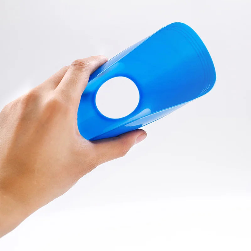 A hand is holding a bright blue soccer training disc cone with a circular opening.