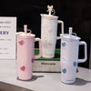 A collection of pink and white insulated thermos mugs, including a large pitcher and two mugs, displayed on a table.