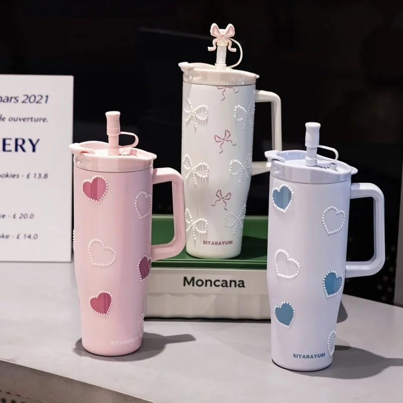 A collection of pink and white insulated thermos mugs, including a large pitcher and two mugs, displayed on a table.