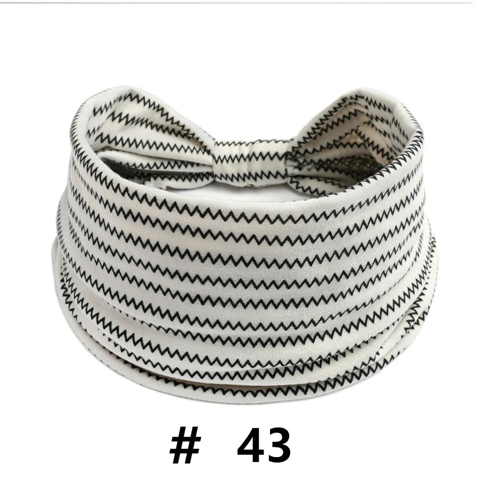 A white knitted headband with black zigzag pattern, shown flat.