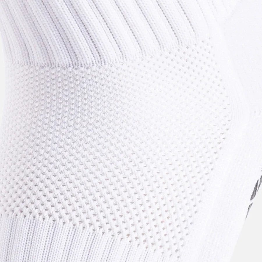 Close-up of white ribbed athletic grip socks on a leg.