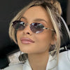 A woman wearing rimless oval gradient sunglasses indoors.