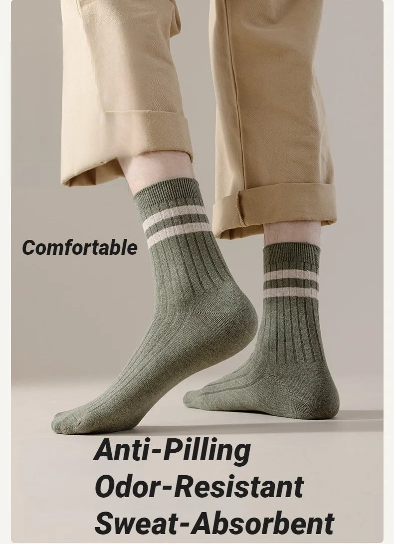 Close-up of beige trousers and a person wearing olive green striped socks with a ribbed cuff.