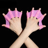 A pair of pink silicone swim training flippers are shown on a person's hands.