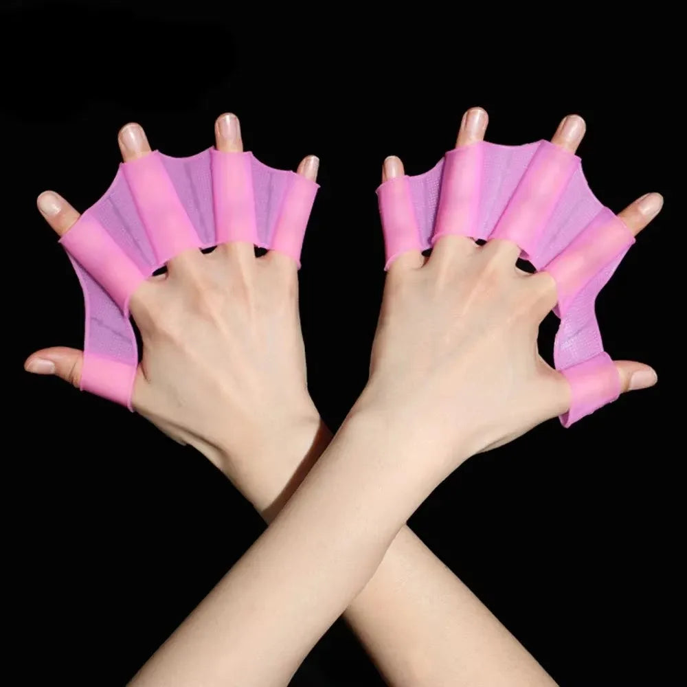 A pair of pink silicone swim training flippers are shown on a person's hands.