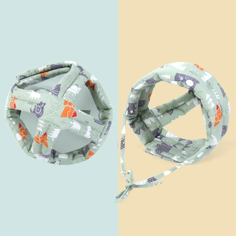 A soft, adjustable safety helmet for toddlers in a light green fabric with various animal patterns.