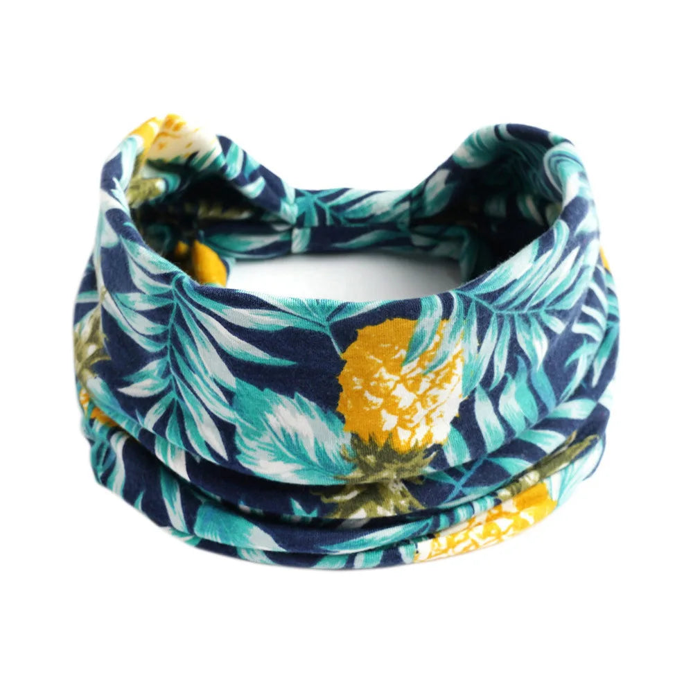 A floral patterned bohemian cotton stretch headband in navy blue, teal, and yellow.