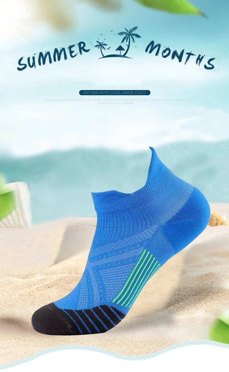 A blue and black performance compression sports sock is displayed on a sandy surface with a tropical background.
