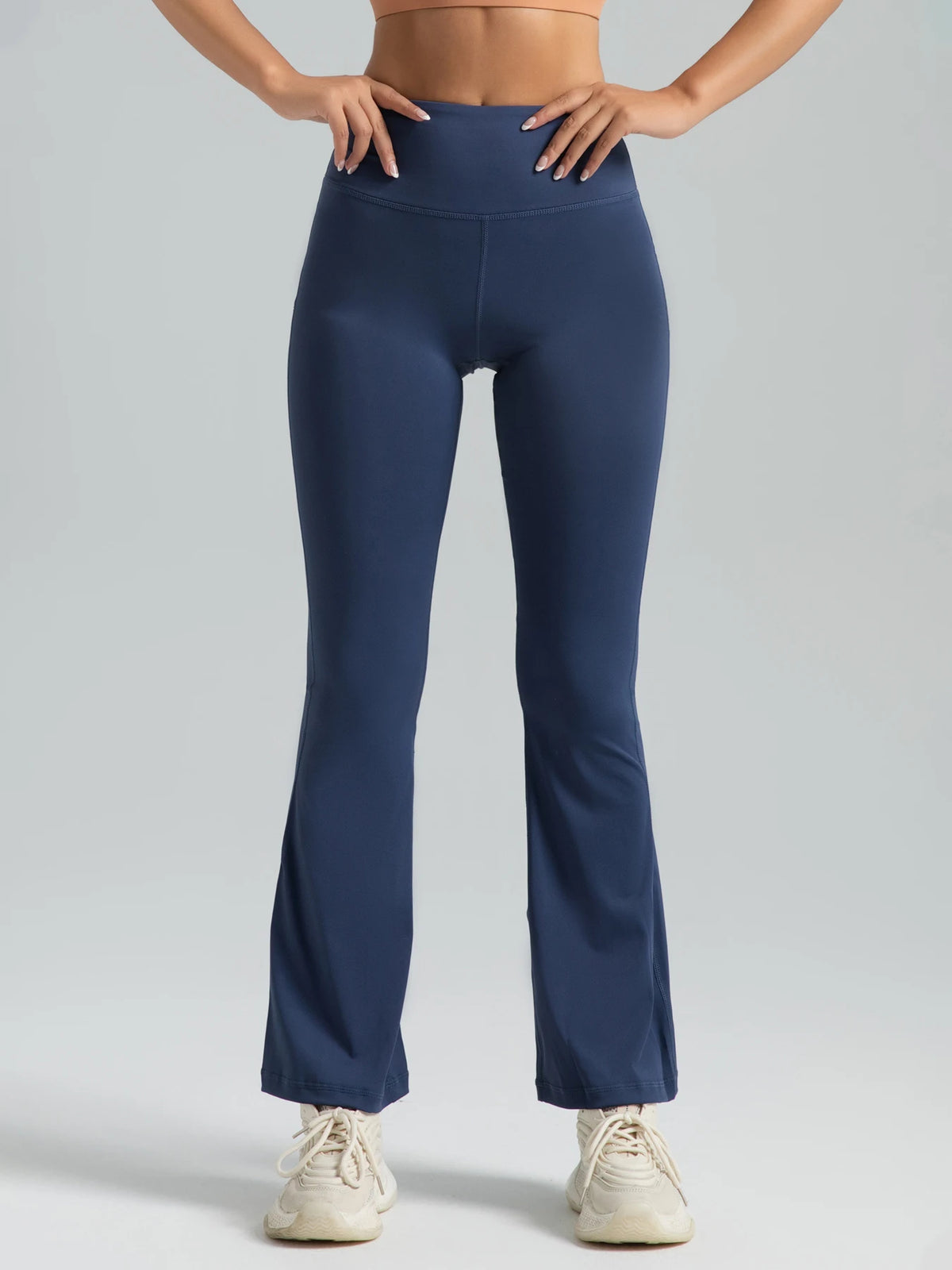 A model wearing dark blue high-waisted bootcut yoga pants and a matching sports bra.