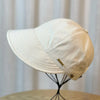Gorra de béisbol de ala ancha y protección UV de color crema exhibida en un soporte negro.