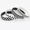 Three checkered silicone wristbands in black and white are displayed on a white background.