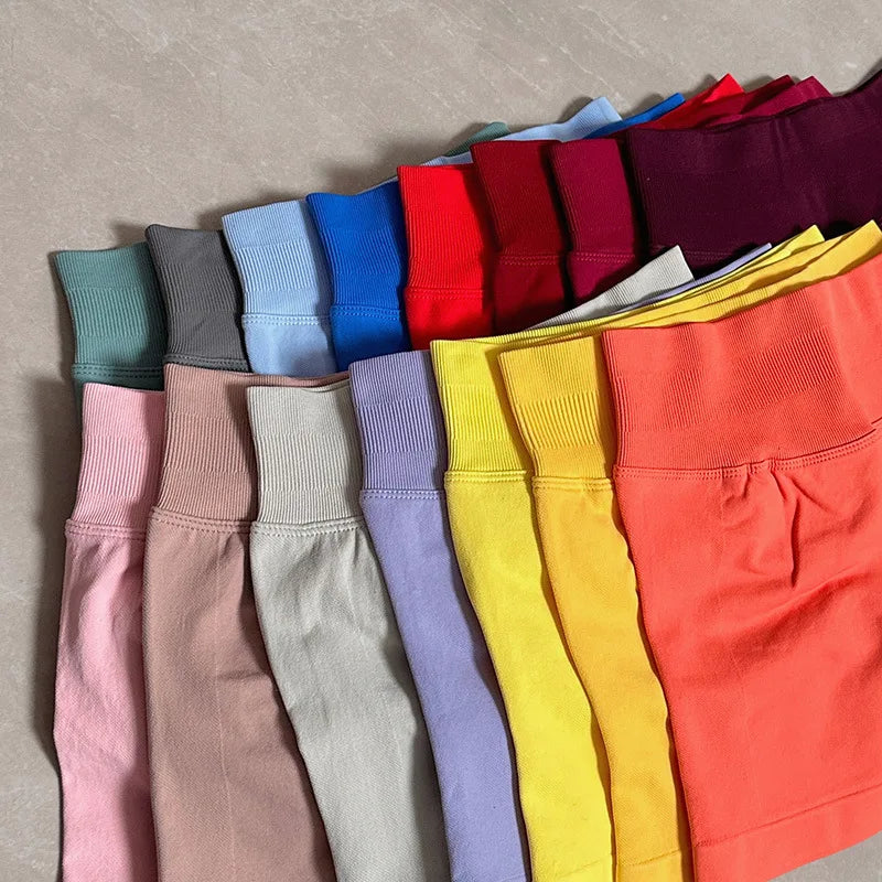 Divers shorts de yoga sans couture à taille haute et de différentes couleurs unies sont présentés en rangée.