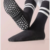 A pair of black non-slip yoga socks with white stripes and polka dots shown on a foot.