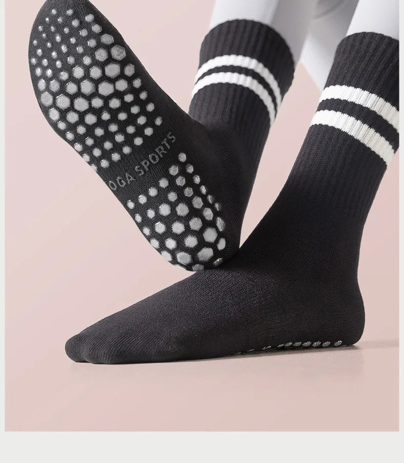 A pair of black non-slip yoga socks with white stripes and polka dots shown on a foot.