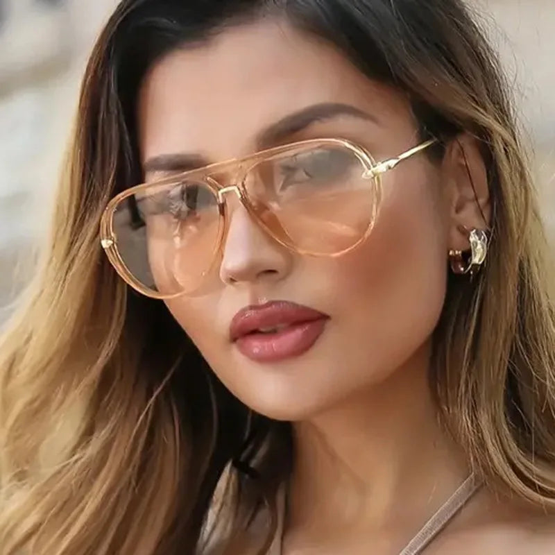 Close-up of a woman wearing gold-toned aviator sunglasses with light brown lenses and long hair.