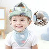 A smiling toddler wearing a soft adjustable safety helmet patterned with clouds and animals.