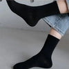 Gros plan sur des chaussettes en tricot noir mi-mollet respirantes portées sur une jambe, assorties à un jean en denim.
