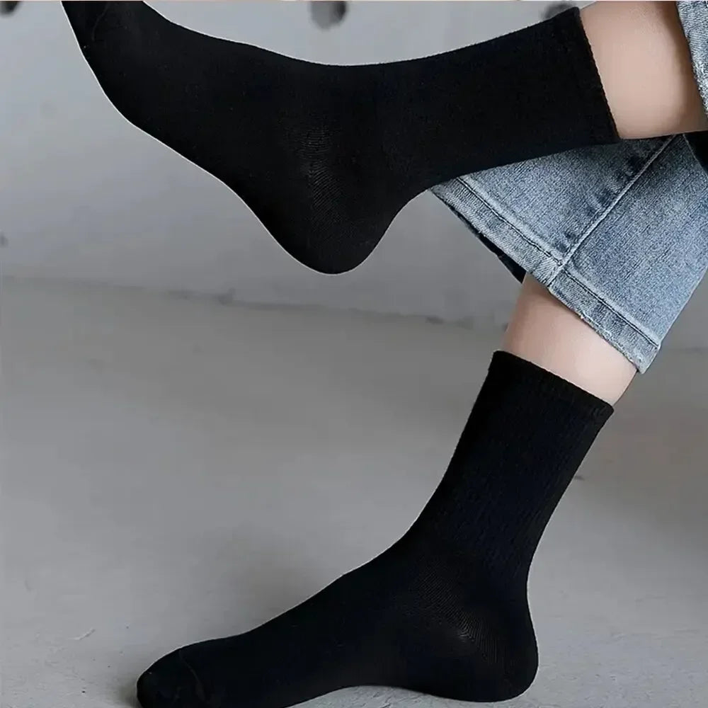 Gros plan sur des chaussettes en tricot noir mi-mollet respirantes portées sur une jambe, assorties à un jean en denim.