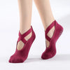 A pair of deep red suede yoga and pilates socks worn on a person's feet.