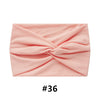 A pink, ruched fabric headband folded into a criss-cross design.