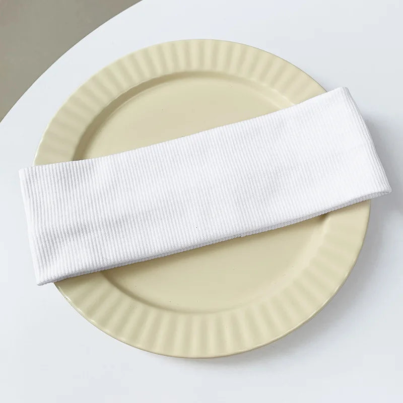 A white ribbed elastic hairband is placed on a light beige plate.