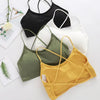 A collection of women's cross strap sports bras in black, white, olive green, and yellow laid out on a white surface.