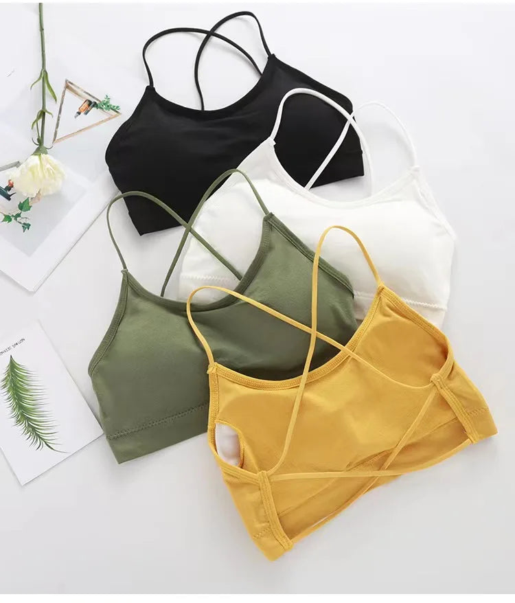 A collection of women's cross strap sports bras in black, white, olive green, and yellow laid out on a white surface.