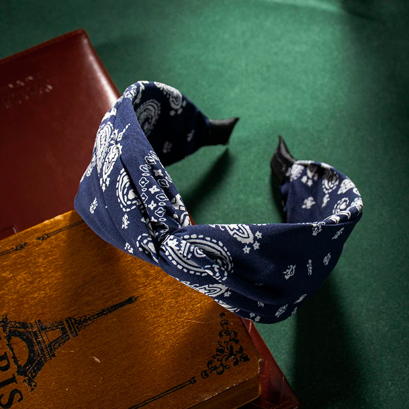 Tela azul marino estampada atada en un lazo, apoyada sobre libros viejos.