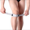 A person is wearing a gray adjustable patella tendon support brace on their knee.