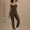 Eine Frau trägt einen dunkel olivgrünen Colorblock-Yoga-Jumpsuit und weiße Sportschuhe.
