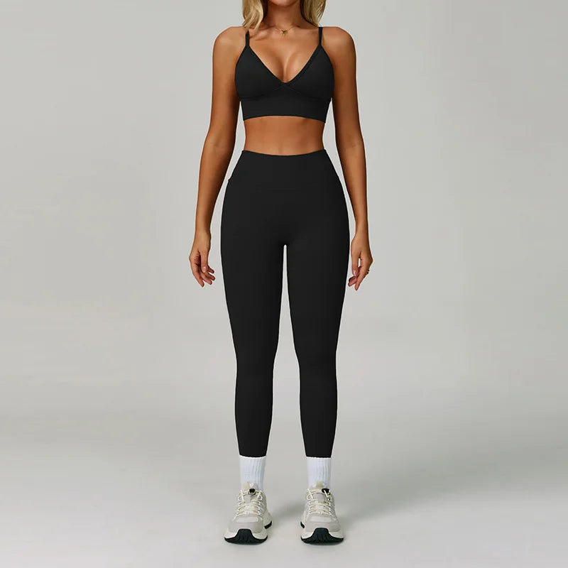 Eine Frau modelliert ein schwarzes, nahtloses Sport-Yoga-Set mit Crop-Top und Langhosen.
