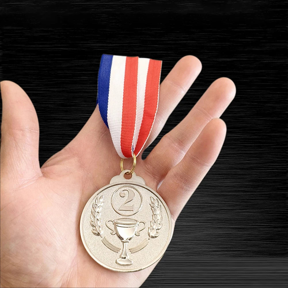A hand holds a gold sports achievement medal with laurel wreaths and a ribbon featuring red, white, and blue stripes.