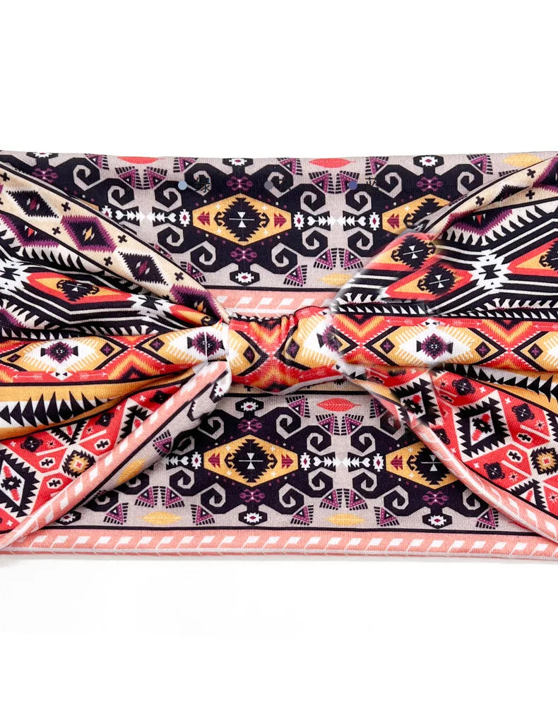A close-up of a bohemian stretch cotton headband featuring intricate geometric patterns in black, pink, and orange.