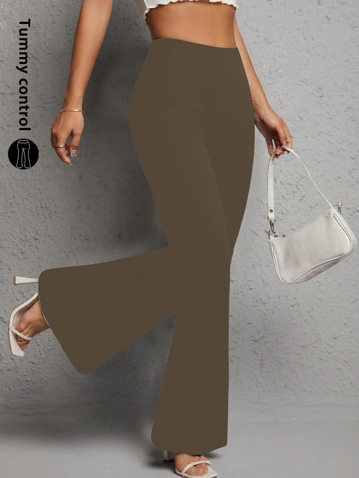 A model wearing olive brown flared yoga trousers and a white shoulder bag.