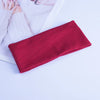 A close-up of a folded red knitted headband resting on a white surface.