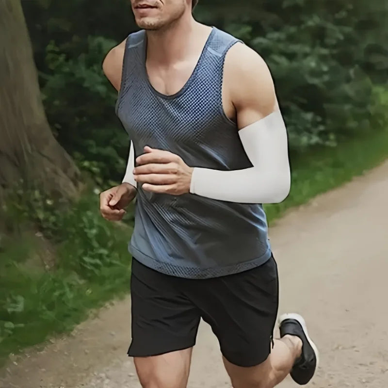 Un hombre con camiseta sin mangas gris y pantalones cortos negros corre al aire libre usando mangas protectoras solares blanc
