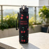 A black reusable water bottle with a silver cap and a design featuring sweet cherry illustrations.