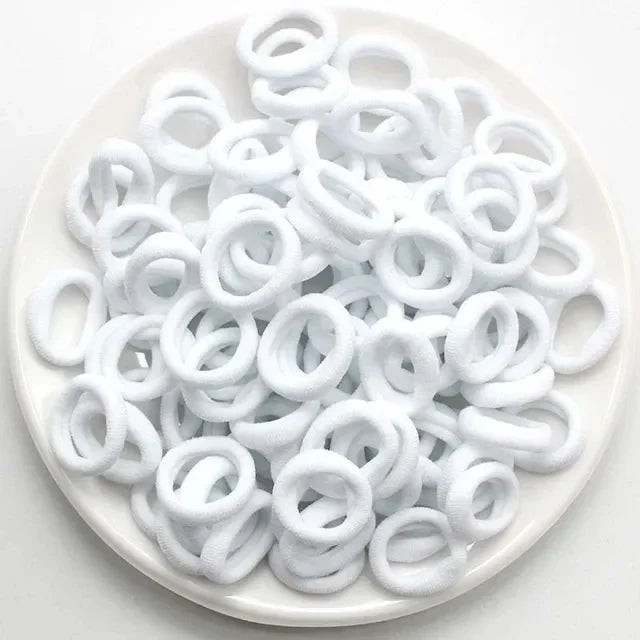 Haufen weißer Nylon-Elasthebändchen auf einem weißen Teller