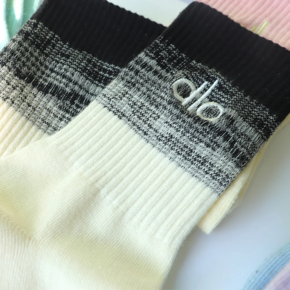 A pair of black and white striped socks with a logo on the cuff, shown folded.