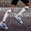 A person wearing white compression socks with American flag designs and gray sneakers is shown in a side view.
