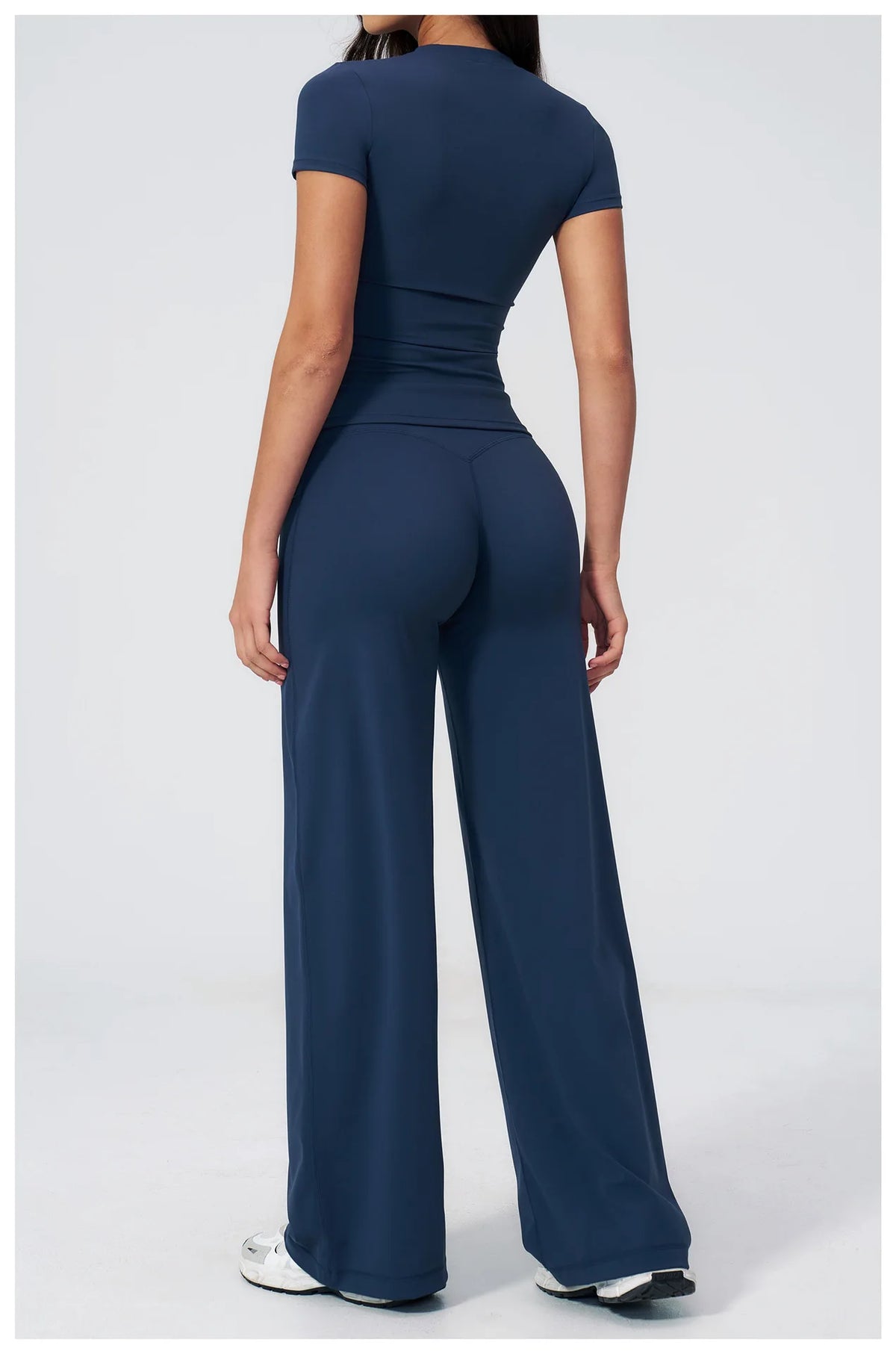 A woman wearing a navy blue high-waist yoga and gym leggings set from the back view.