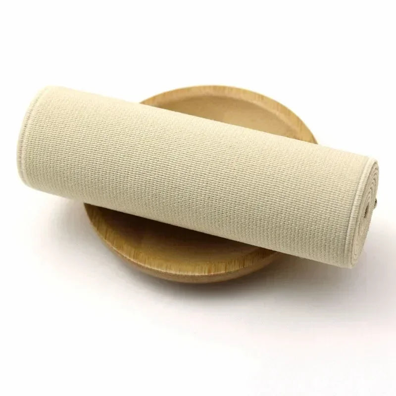 A roll of beige elastic bands resting on a wooden disk.