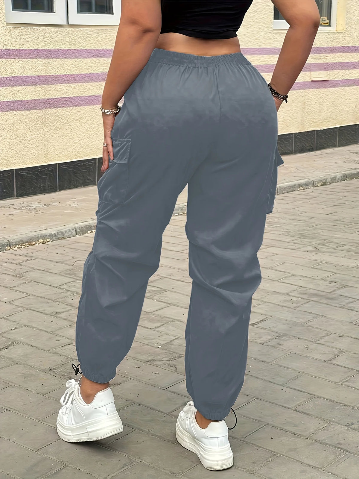 A person wearing gray high-waist drawstring cargo joggers standing outdoors.
