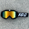 A pair of black goggles with orange-tinted lenses and a white '100' logo on the strap, resting on a gray surface.