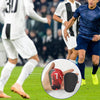 Una mano sostiene una espinillera de fútbol roja contra un fondo de césped verde.