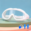 White swimming goggles with clear lenses resting on a light green surface.