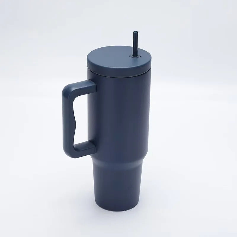 Tasse isotherme en acier inoxydable gris foncé avec anse et paille, vue de côté.