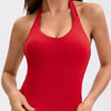 A woman wearing a red seamless sports camisole top and matching bottoms for yoga or fitness.