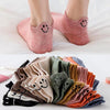 A stack of 10 pink and beige kawaii embroidered ankle socks in various colors is displayed on a white surface.